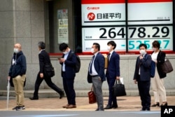 People wearing protective masks stand in front of an electronic stock board showing Japan's Nikkei 225 index at a securities firm, in Tokyo, May 9, 2022.
