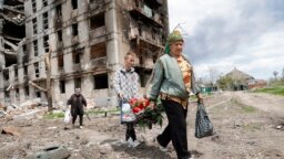 Stanovnici Marijupolja prolaze pored stambene zgrade razorene u ruskom bombardovanju