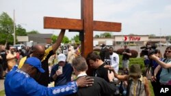 A group prays at a memorial for the victims of the Buffalo supermarket shooting outside the Tops Friendly Market, May 22, 2022, Tops was encouraging people to join its stores in a moment of silence to honor the shooting victims Saturday at 2:30 p.m.