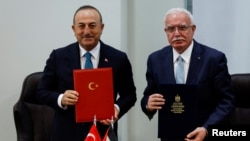 Menlu Turki Mevlut Cavusoglu (kiri) dan Menlu Palestina Riyad al-Maliki menandatangani kesepakatan usai pembicaraan di Ramallah, Tepi Barat, Selasa 24 Mei 2022.