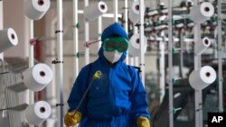 Seorang pegawai dari pabrik pakaian Songyo di Distrik Songyo, Pyongyang, Korea Utara, menyemprotkan disinfektan ke area pabrik di tengah perebakan COVID-19 di negara tersebut, pada 18 Mei 2022. (Foto: AP/Jon Chol Hin)
