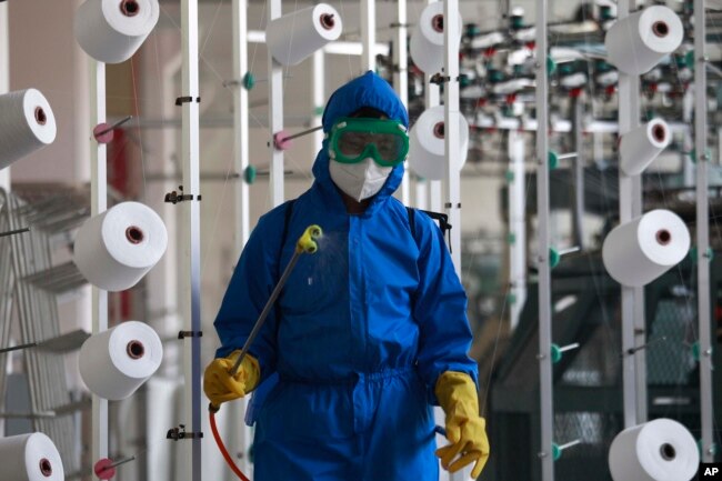 An employee of Songyo Knitwear Factory in Songyo district disinfects the work floor in Pyongyang, North Korea, May 18, 2022, after Kim Jong Un said Tuesday his party would treat the country's outbreak under the state emergency. (AP Photo/Jon Chol Jin)