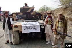 FILE - Armed militants of Tehrik-i-Taliban Pakistan pose for photographs next to a captured armored vehicle in the Pakistan-Afghanistan border town of Landikotal on Nov. 10, 2008.