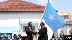 Outgoing Somalia President Mohamed Abdullahi Mohamed, left, also known as Farmaajo, presents the Somali flag to newly elected President Hassan Sheikh Mohamud on May 23, 2022. 