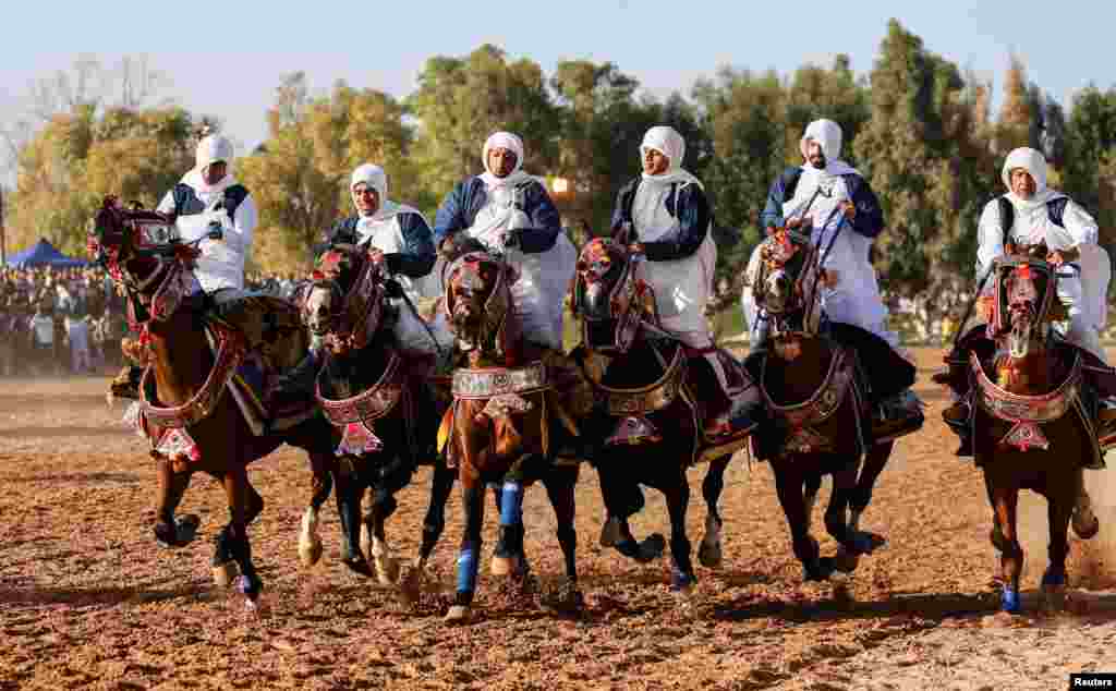 Men wearing traditional costumes ride horses during a horse race in Misrata, Libya, May 24, 2022.