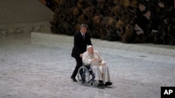 FILE - Pope Francis arrives in a wheelchair to attend an audience with nuns and religious superiors in the Paul VI Hall at The Vatican, May 5, 2022.
