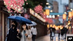 FILE - People walk through a shopping street along the famed Sensoji temple in the Asakusa neighborhood in Tokyo, April 29, 2021.