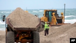 A dump truck brings another load of sand to an eroded beach in North Wildwood, New Jersey. A bulldozer spreads out sand, May 24, 2022. (File Photo)