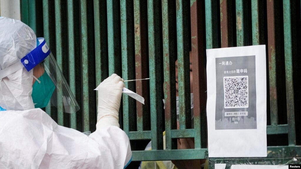 上海一名医务人员从一个固定新冠核酸采样点里给市民进行检测。（2022年5月5日）(photo:VOA)