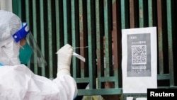 上海一名醫務人員從一個固定新冠核酸採樣點裡給市民進行檢測。（2022年5月5日）