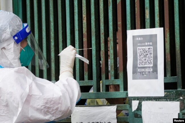 Seorang pekerja medis dengan pakaian pelindung mengambil sampel swab dari seorang warga, di tengah pandemi COVID-19, di Shanghai, Cina, 5 Mei 2022. (Foto: REUTERS/ Lagu Ali)