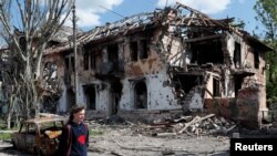 A local resident walks past a building heavily damaged during the Ukraine-Russia conflict in the southern port city of Mariupol, Ukraine, May 20, 2022.