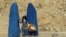 FILE - Afghan women clad in burkas wait for transportation on a road in Kabul, Nov. 5, 2012.
