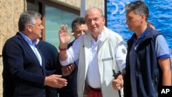 Spain's former King Juan Carlos (center), waves before a reception at a nautical club prior to a yachting event in Sanxenxo, Spain, on May 20, 2022. The former king returned to Spain for his first visit since leaving nearly two years ago amid a cloud of financial scandals. 