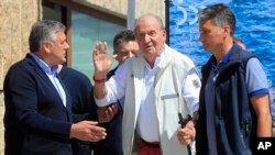 Mantan Raja Spanyol Juan Carlos, tengah, melambaikan tangannya kepada para peserta yang hadir dalam acara perlombaan kapal layar di Sanxenxo, Spanyol, pada 20 Mei 2022. (Foto: AP/Lalo R. Villar)