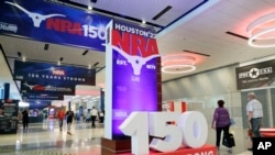 Convention attendants walk past some of the signage in the hallways outside of the exhibit halls at the NRA Annual Meeting held at the George R. Brown Convention Center, May 26, 2022, in Houston. 