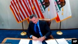 FILE - In this image made from video from the Office of the Governor, California Gov. Gavin Newsom signs into law a bill that establishes a task force to come up with recommendations on how to give reparations to Black Americans on Sept. 30, 2020, in Sacr