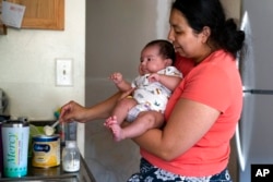 Yury Navas, 29, of Laurel, Md., scoops formula to make a bottle for her infant son, Jose Ismael Gálvez, 2 months, from her dwindling supply of formula at their apartment in Laurel, Md., May 23, 2022.