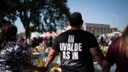 Pastor Humberto Renovato, in a T-shirt reading "In Uvalde As In Heaven," leads a prayer circle at a memorial site for victims killed in the Robb Elementary School shooting, May 28, 2022, in Uvalde, Texas.