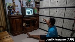 Ilustrasi - Pesepakbola disabilitas Syaiful Arifin menonton televisi di rumahnya di Surabaya. (Foto: AFP/Juni Kriswanto).