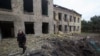 A police officer walks by a school building damaged by a Russian military strike, as Russia's attack on Ukraine continues in the Donetsk region on May 22, 2022. On Tuesday, a Ukrainian official asked other governments to send more weapons to help Ukraine fight Russian forces.