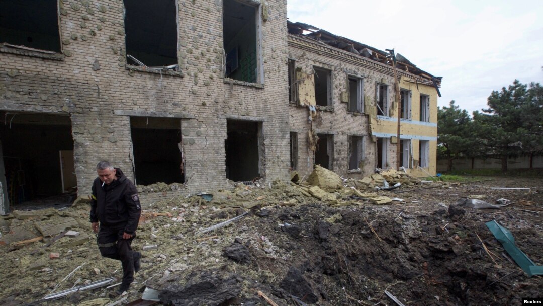 A police officer walks by a school building damaged by a Russian military strike, as Russia's attack on Ukraine continues in the Donetsk region on May 22, 2022. On Tuesday, a Ukrainian official asked other governments to send more weapons to help Ukraine fight Russian forces.