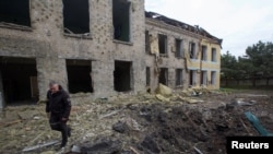 A police officer walks by a school building damaged by a Russian military strike, as Russia's attack on Ukraine continues in the Donetsk region on May 22, 2022. On Tuesday, a Ukrainian official asked other governments to send more weapons to help Ukraine fight Russian forces.