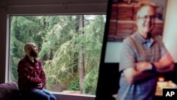 Nathan Lambrecht is photographed next to a picture of his father, Doug Lambrecht, at his apartment in Woodinville, Wash., March 21, 2022. The 71-year-old retired physician was among the first of the nearly 1 million Americans to die from COVID-19.