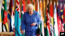 FILE - Britain's Queen Elizabeth II walks past Commonwealth flags in St. George's Hall at Windsor Castle, England, to mark Commonwealth Day in this image that was issued March 6, 2021.