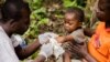 FILE - A child affected by monkeypox, sits on his father's legs while receiving treatment at a center run by Doctors Without Borders, in Zomea Kaka, in Lobaya region, Central African Republic, Oct. 18, 2018.
