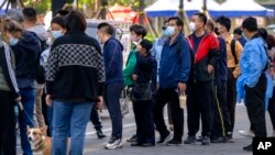 People stand in line for COVID-19 tests at a testing site after authorities ordered a third round of three consecutive coronavirus tests for residents in the Chaoyang district of Beijing, May 7, 2022.