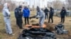 Tim investigasi forensik Prancis, yang tiba di Ukraina untuk menyelidiki dugaan kejahatan perang, beridir di dekat kuburan massal di Kota Bucha, Ukraina, pada 12 April 2022. (Foto: AP/Wladyslaw Musiienko)
