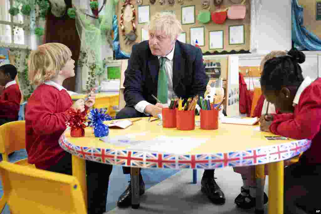 British Prime Minister Boris Johnson sits at a desk with some pupils as he pays a visit to St. Mary Cray Primary Academy, in Orpington, England, to see how they are delivering tutoring to help children catch up following the pandemic.