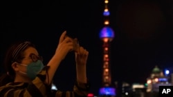 A woman takes photos near the Oriental Pearl Tower on the bund, Tuesday, May 31, 2022, in Shanghai. (AP Photo/Ng Han Guan)