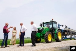 President Joe Biden listens to Jeff and Gina O'Connor, owners of O'Connor Farms, as Agriculture Secretary Tom Vilsack looks on at right, in Kankakee, Ill., May 11, 2022.