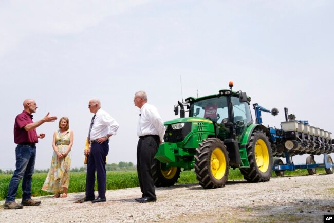 President Joe Biden listens to Jeff and Gina O'Connor, owners of O'Connor Farms, as Agriculture Secretary Tom Vilsack looks on at right, in Kankakee, Ill., May 11, 2022.