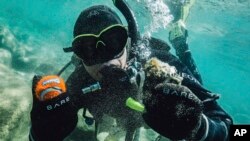 In this photo provided by Clean Up The Lake, CUTL diver Colin West shows debris found in the lake from an initial dive in 2020, at Lake Tahoe, Nev. 
