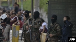 Soldados salvadoreños custodian las afueras de la prisión La Esperanza mientras familiares de hombres con presuntos vínculos con pandillas capturados durante el estado de emergencia esperan información en San Salvador, el 17 de mayo de 2022.