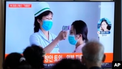 People watch a TV screen showing a news report about the COVID-19 outbreak in North Korea, at a train station in Seoul, South Korea, May 14, 2022. 