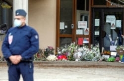 Flowers are stacked outside the school where slain history teacher Samuel Paty was working, in Conflans-Sainte-Honorine, northwest of Paris, Oct. 17, 2020.