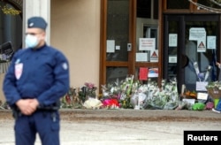 Flowers are stacked outside the school where slain history teacher Samuel Paty was working, in Conflans-Sainte-Honorine, northwest of Paris, Oct. 17, 2020.