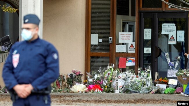 Flowers are stacked outside the school where slain history teacher Samuel Paty was working, in Conflans-Sainte-Honorine, northwest of Paris, France, Oct. 17, 2020.