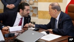 In this photo released by the Lebanese Government, Lebanese President Michel Aoun, right, speaks with Prime Minister Saad Hariri, at the Presidential Palace in Baabda, east of Beirut, Lebanon, Dec. 5, 2017.