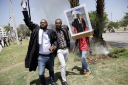 FILE - Men carry a picture depicting lawyer and President of the Bar of Lawyers of Port-au-Prince Monferrier Dorval, who was killed on Aug. 28, during a march to demand justice, in the streets of Port-au-Prince, Haiti, Sept. 3, 2020.