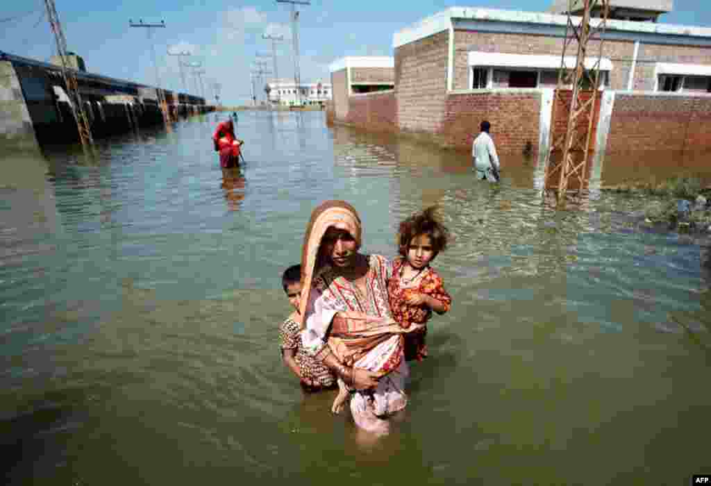 Phụ nữ trong tỉnh Sindh của Pakistan đưa con đến vùng đất cao sau khi khu nhà của bà bị ngập lụt. REUTERS/Akhtar Soomro