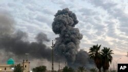 Plumes of smoke rise after an explosion at a military base southwest of Baghdad, Iraq, Aug. 12, 2019