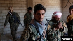 FILE - Kurdish fighters from the People's Protection Units (YPG) stand in a house in Raqqa, Syria, June 21, 2017. While welcoming the ouster of jihadist from the city, local Arabs are suspicious of the advancing Kurds' long-term intentions.