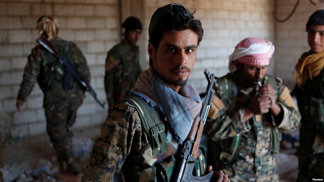 FILE - Kurdish fighters from the People's Protection Units (YPG) stand in a house in Raqqa, Syria, June 21, 2017. 