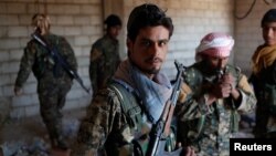 Kurdish fighters from the People's Protection Units (YPG) stand in a house in Raqqa, Syria, June 21, 2017. 