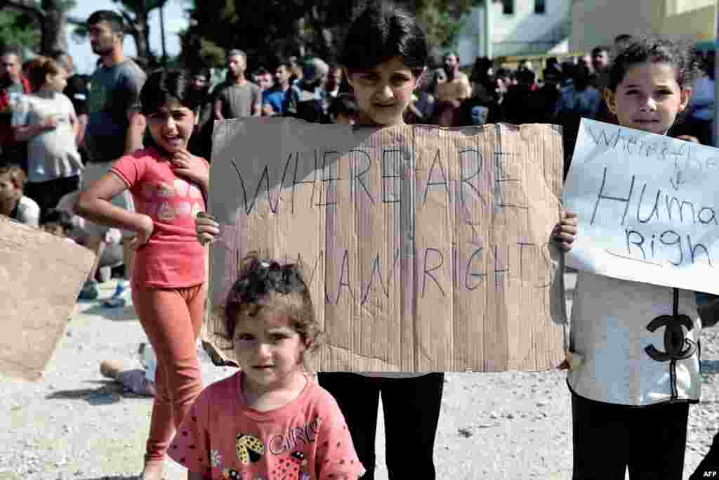کودکان مهاجر و پناهجو که در یک اردوگاه پناهجویان در نزدیکی شهر تسالونیکی یونان با پلاکاردی در دستشان. نوشته: حقوق بشر کجاست؟ 
